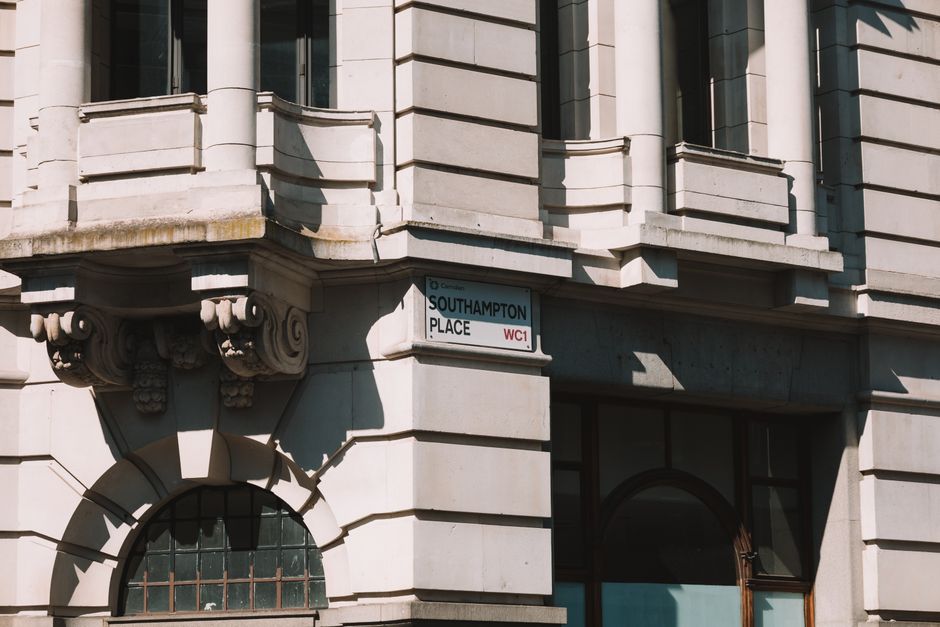 The image shows a close-up view of a corner of a brick building with two street signs attached to the wall. The sign on the left indicates 'Lincoln's Inn Fields, Borough of Holborn, leading to Gate St